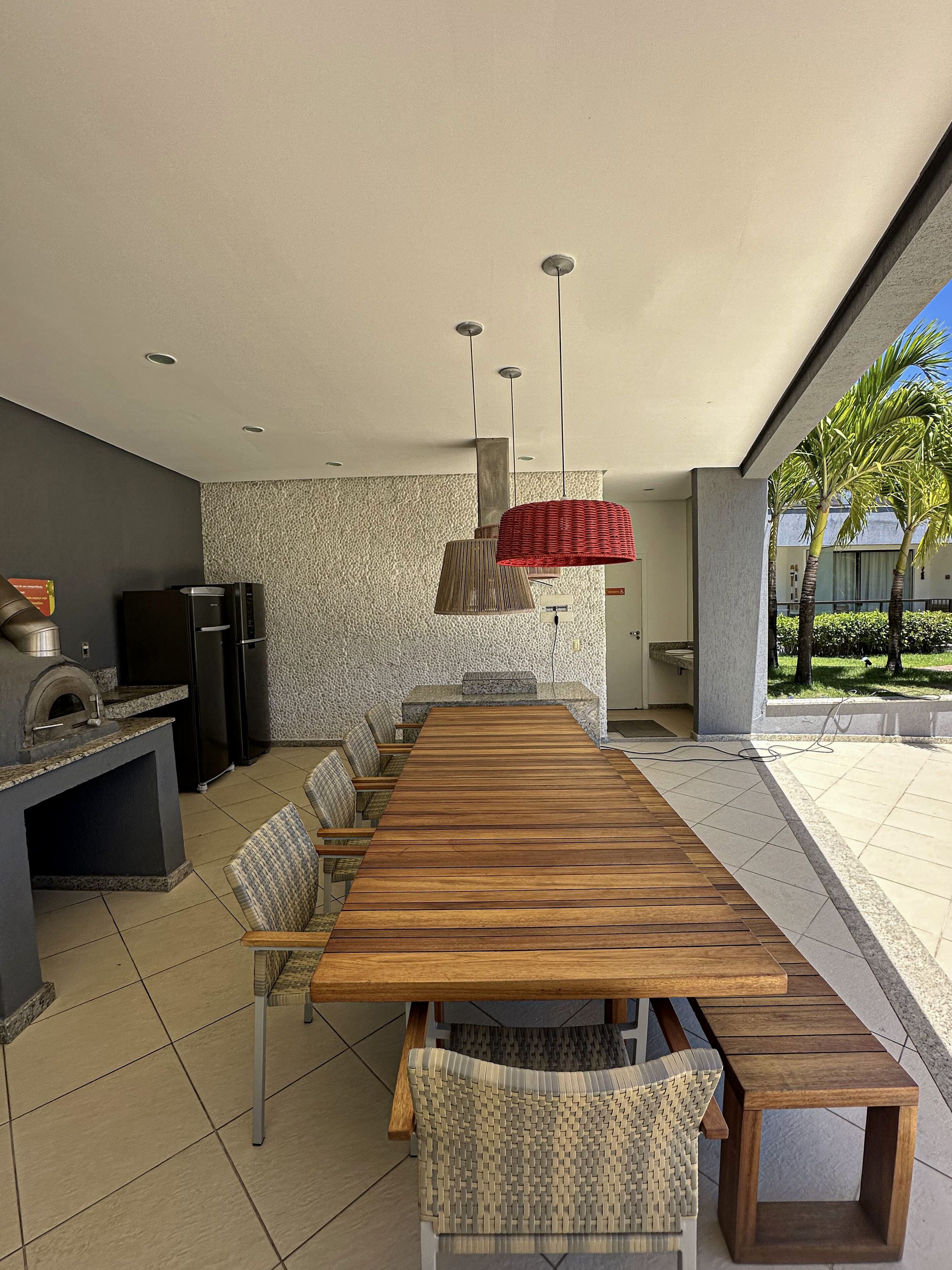 Una cocina moderna con una mesa de madera larga y sillas, horno empotrado y salpicadero de piedra.