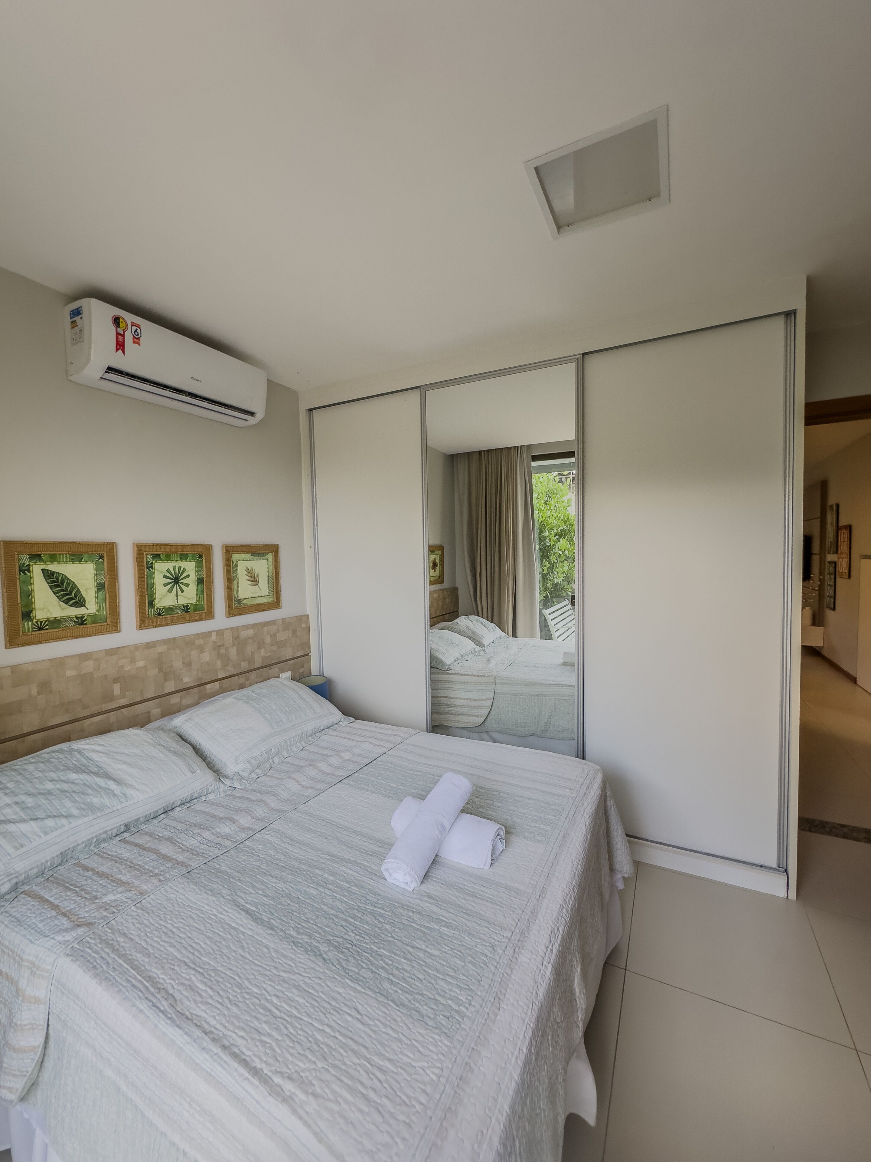 Habitación de hotel con una cama grande, aire acondicionado y puerta corredera a un balcón.