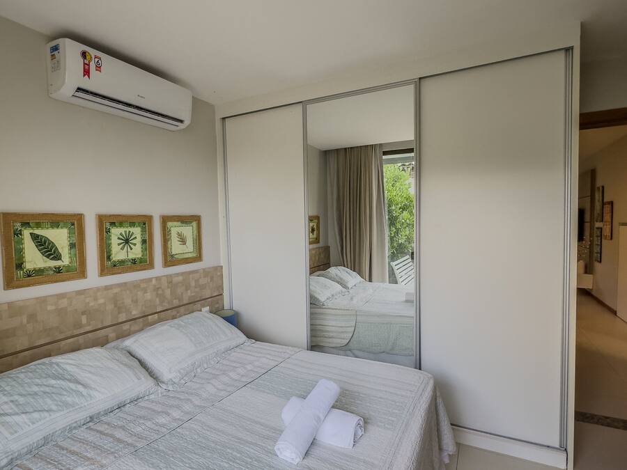 Habitación de hotel con una cama grande, aire acondicionado y puerta corredera a un balcón.