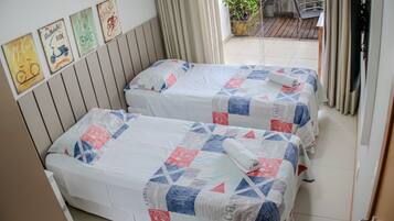 Two beds with matching quilts, a wooden headboard, and a view of an outdoor patio area.