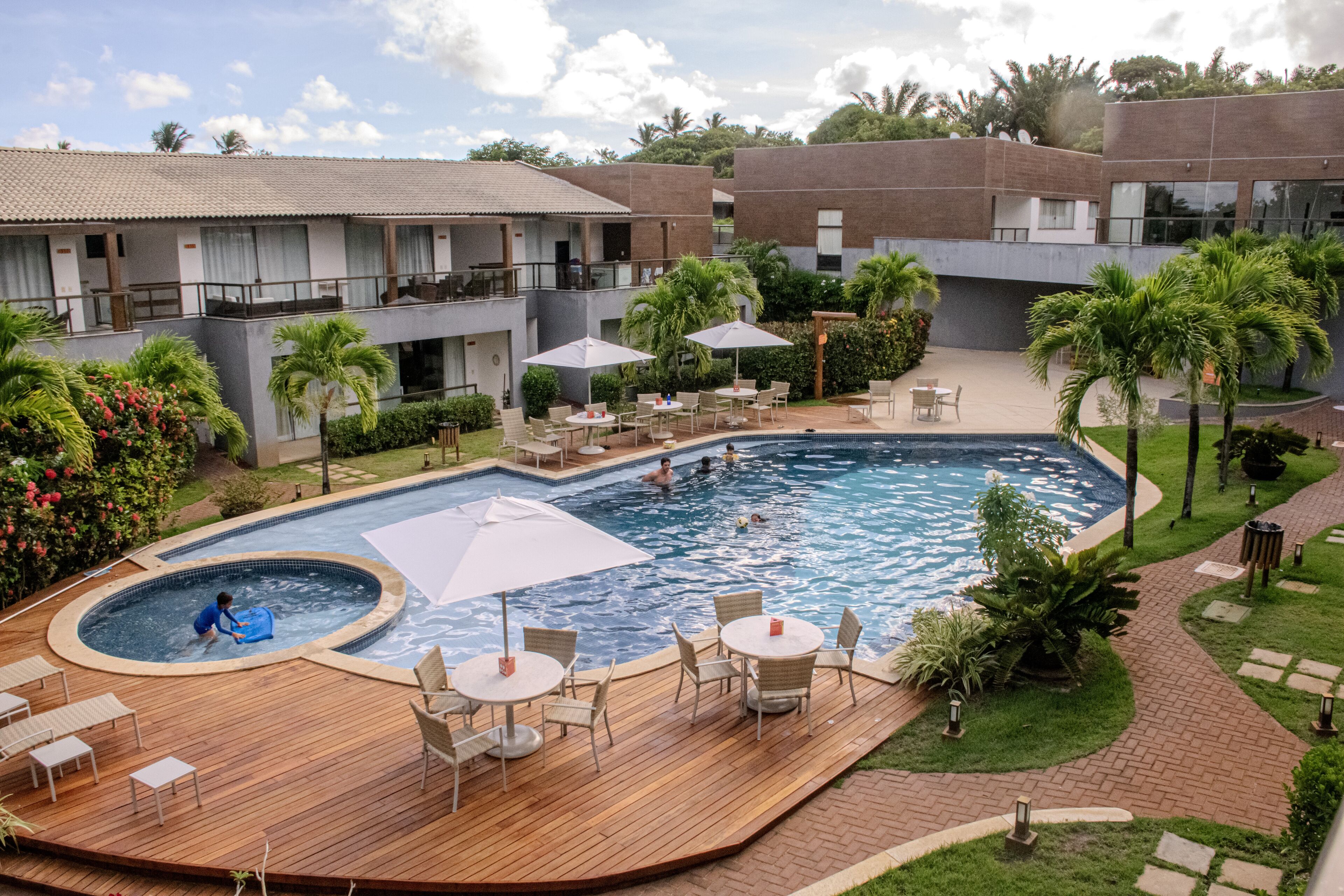 A hotel with a swimming pool, outdoor seating, and lush landscaping.