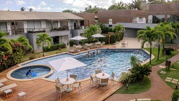 A hotel with a swimming pool, outdoor seating, and lush landscaping.