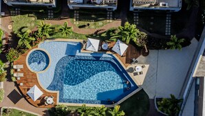 An aerial view of a resort with a large swimming pool, sun loungers, and palm trees. - Imbassaí Apartments (Mata de São João)