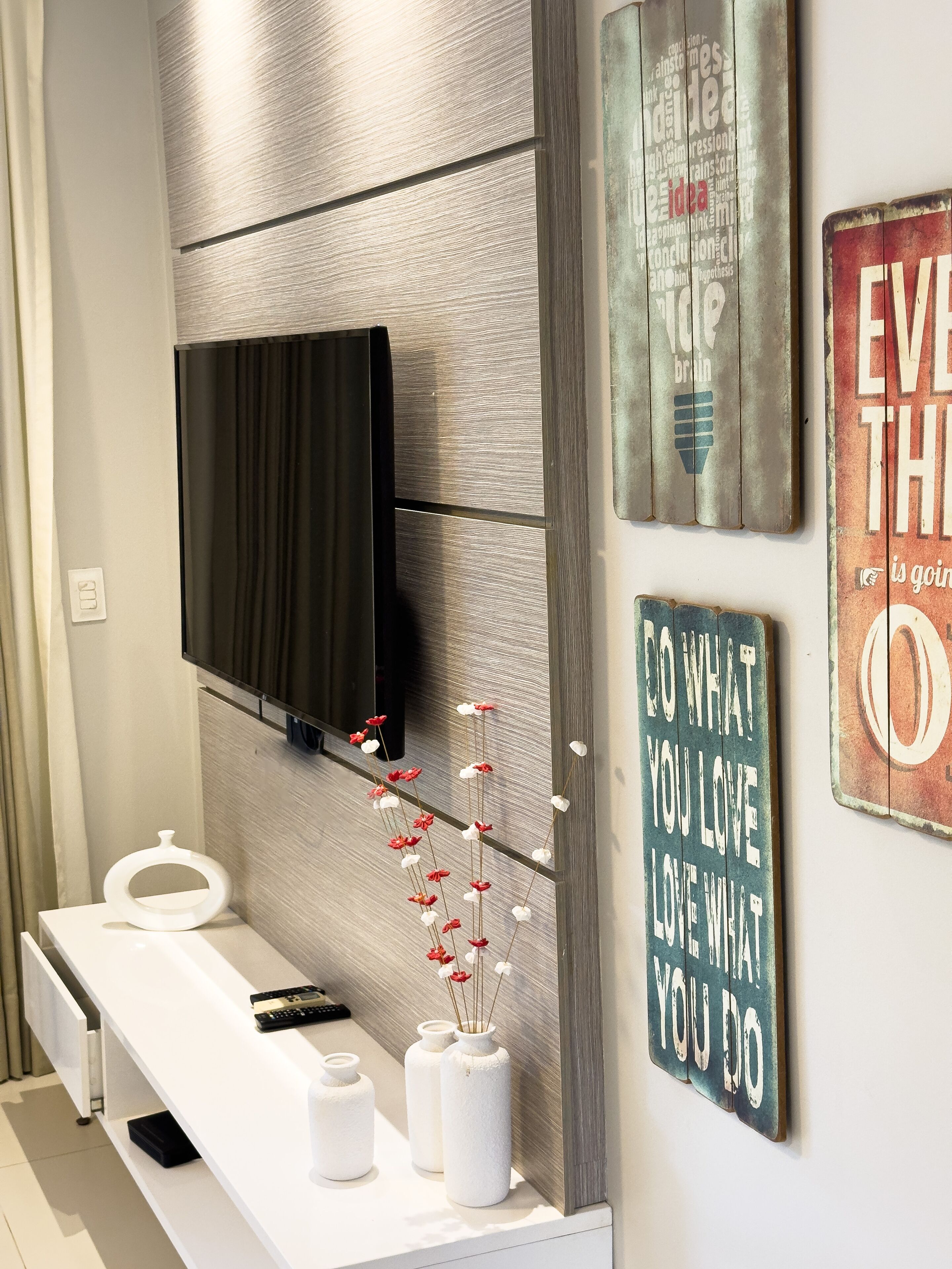 Een moderne badkamer met een grote spiegel, een wandtelevisie en een plank met toiletartikelen.