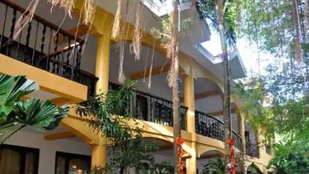 A multi-level hotel atrium with balconies, large windows, and lush indoor plants.