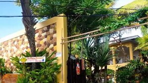A building with a stone facade, a sign for 'Ho Place Restaurant', and lush tropical vegetation.