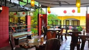 An indoor restaurant with tables and chairs, a red pillar, and hanging lanterns.