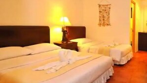 A hotel room with two beds, a bedside table with a lamp, and a wall hanging.