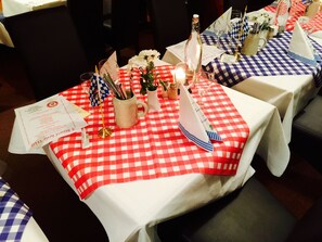 A table set with a checkered tablecloth, a candle, a bottle, salt and pepper shakers, a small flag, and a menu. - Erlebnis Hotel Chiemgauer Hof (Inzell)