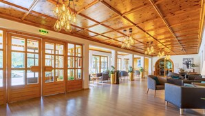 Un vestíbulo amplio con suelo de madera, ventanas grandes y luminarias modernas.