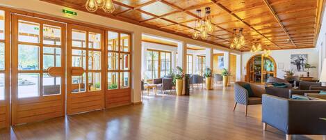 Un vestíbulo amplio con suelo de madera, ventanas grandes y luminarias modernas.