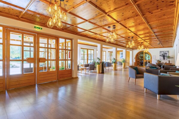 A spacious lobby with wooden flooring, large windows, and modern lighting fixtures. - Erlebnis Hotel Chiemgauer Hof (Inzell)