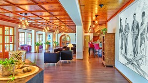 A spacious lobby with wooden ceiling beams, hanging pendant lights, and a large mural on the right wall. - Erlebnis Hotel Chiemgauer Hof (Inzell)