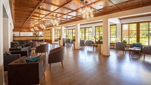Un lobby espacioso con techos altos, vigas de madera y amplias ventanas que ofrecen vistas al exterior.