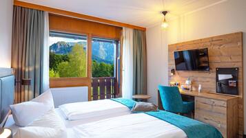 Ein Hotelzimmer mit Bett, Schreibtisch, Stuhl, Fernseher und Bergblick.