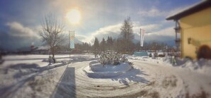 A snowy landscape with a clear sky, a snow-covered bush in the center, and a building on the right. - Erlebnis Hotel Chiemgauer Hof (Inzell)