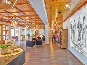 A spacious lobby with wooden ceiling beams, pendant lighting, and a large wall mural. - Erlebnis Hotel Chiemgauer Hof (Inzell)