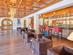 A bar area with wooden ceiling and a bar counter with various bottles. There are several chairs and a staircase leading to another level. - Erlebnis Hotel Chiemgauer Hof (Inzell)
