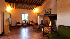 A cozy living room with a fireplace, wooden ceiling beams, and comfortable seating. - Sarna Residence (San Quirico d'Orcia)
