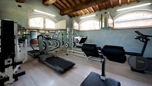 Un gimnasio con cintas de correr, máquinas de pesas y un espejo grande.