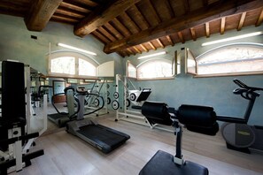 Une salle de sport équipée de tapis de course, d’appareils de musculation et d’un mur recouvert de miroirs.
