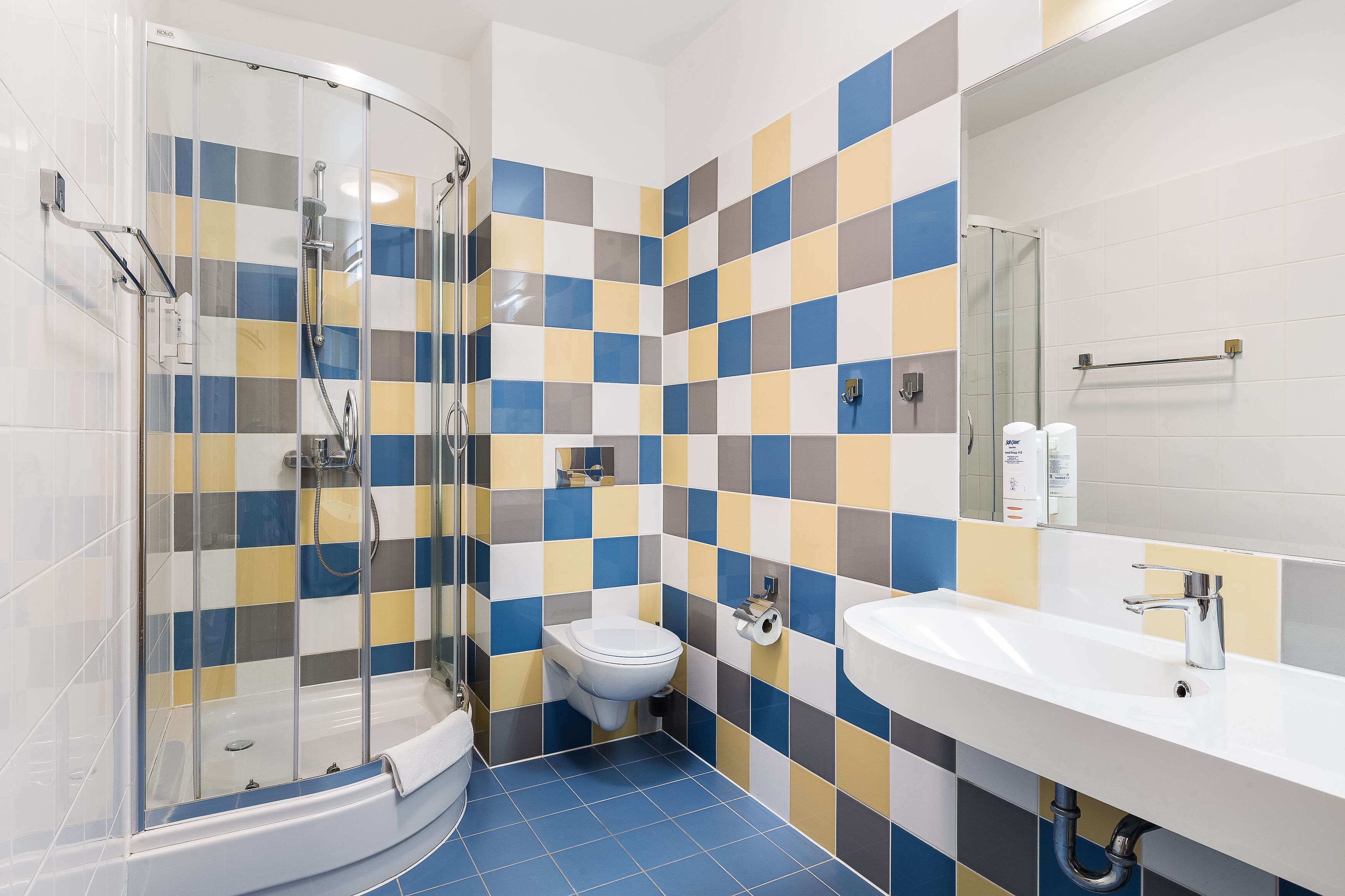 A bathroom with a glass shower enclosure, a toilet, and a sink with a mirror.