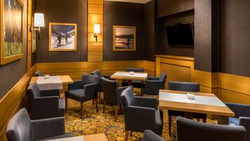 A hotel room with a wooden accent wall, a flat-screen TV, and a seating area with tables and chairs.