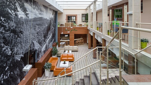 Un vaste atrium doté d’un haut plafond, d’une fresque murale et d’un espace détente avec des canapés et des tables.