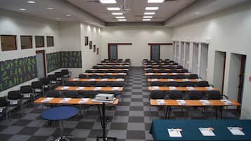 Ein Konferenzraum mit Tischen und Stühlen, einem Projektor und einem Schachbrettmuster auf dem Boden.
