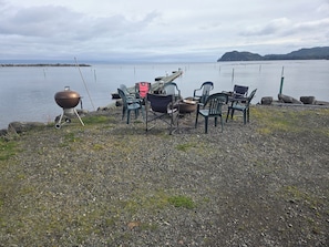 Un entorno junto al lago con una parrilla, sillas y vistas al agua.
