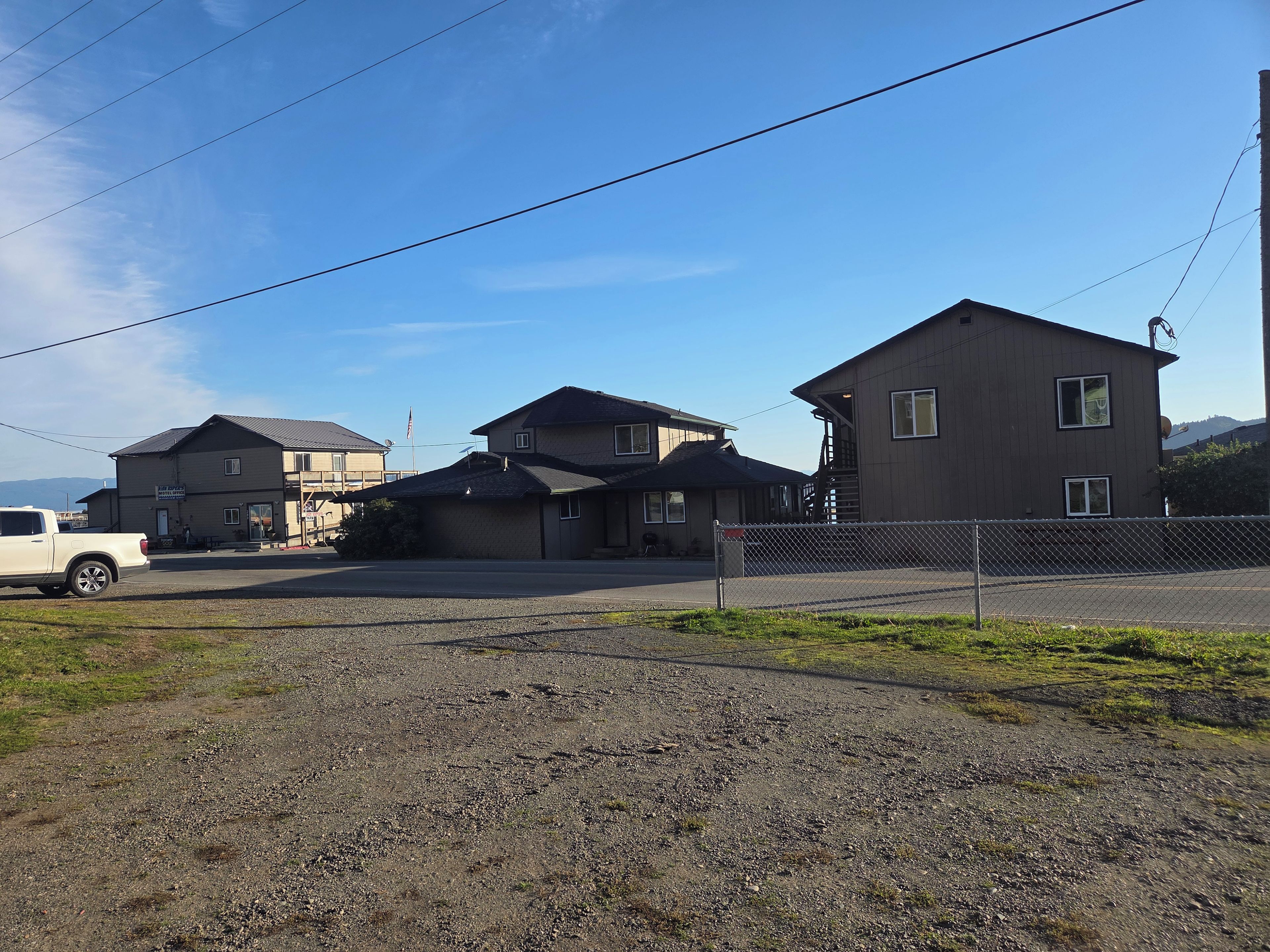 A residential area with multiple houses, a gravel driveway, and a parked white truck.