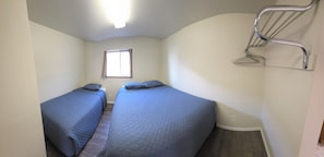 Una habitación con dos camas, una ventana y una estructura metálica.