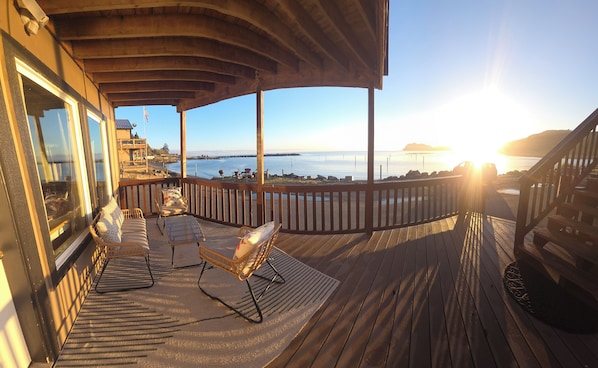 A wooden deck with outdoor seating, a view of the water, and a sunset. - Van Riper's Resort (Sekiu)