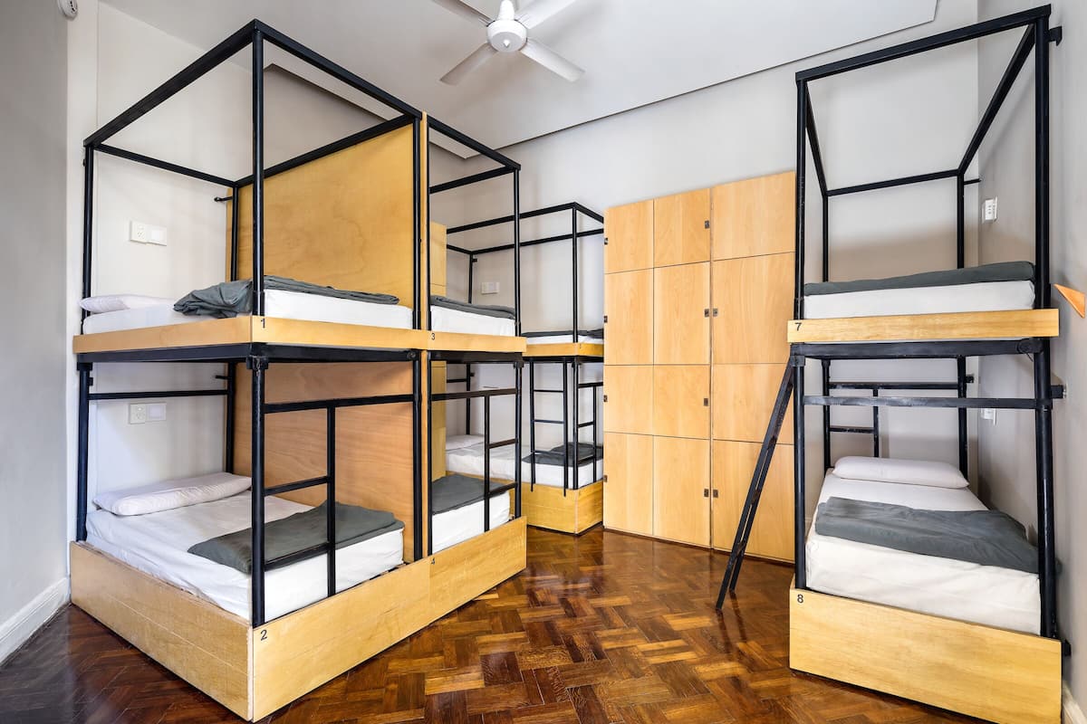 Un dormitorio con literas, suelo de madera y ventilador de techo.