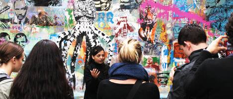 Un espacio público concurrido, con paredes llenas de grafitis y gente observando.