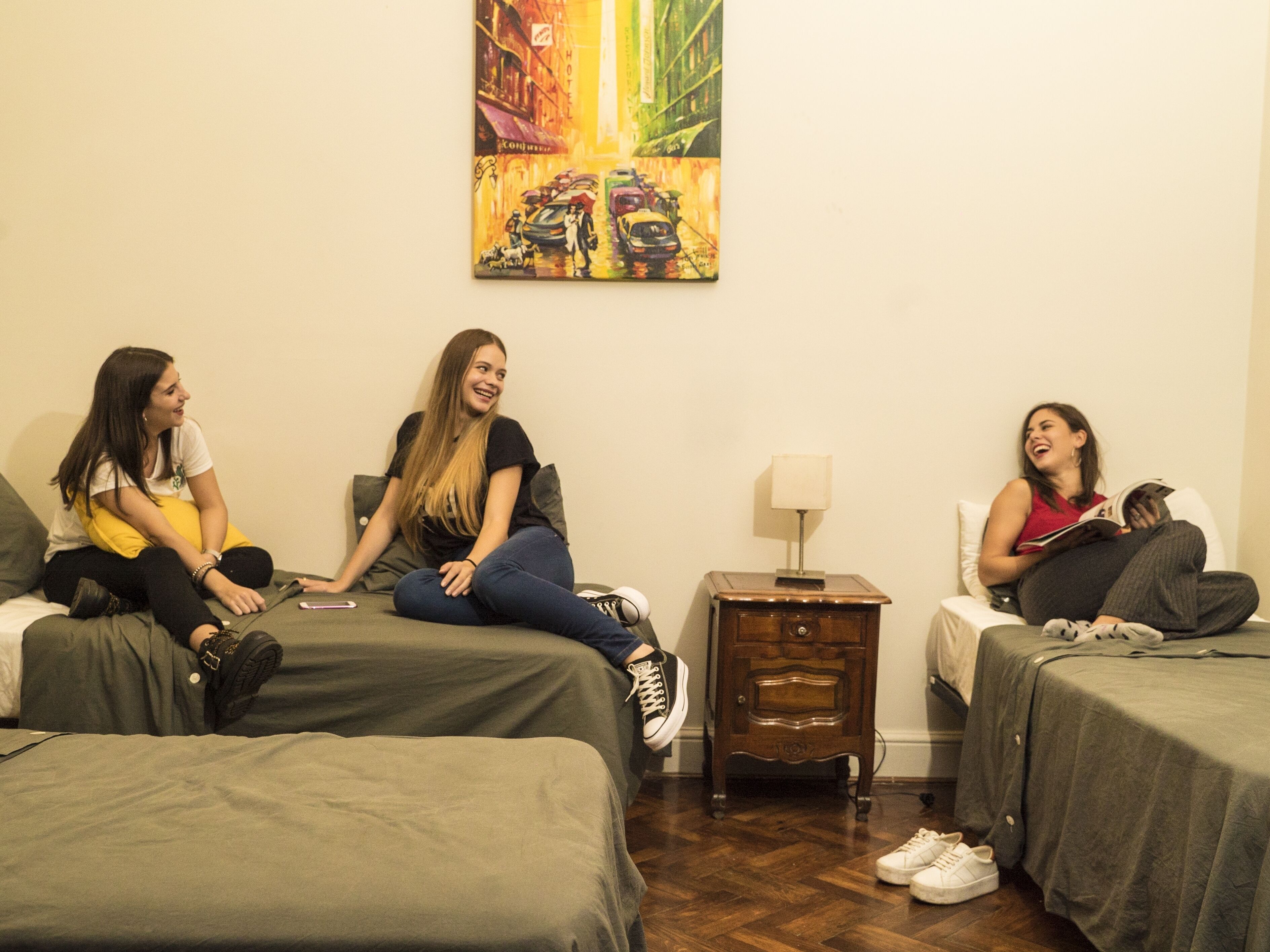 Une chambre avec trois lits, une table de chevet et un tableau au mur.