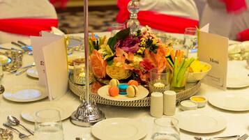 Uma mesa posta para um evento formal, com um arranjo central, cartões de menu e diversos utensílios de mesa.
