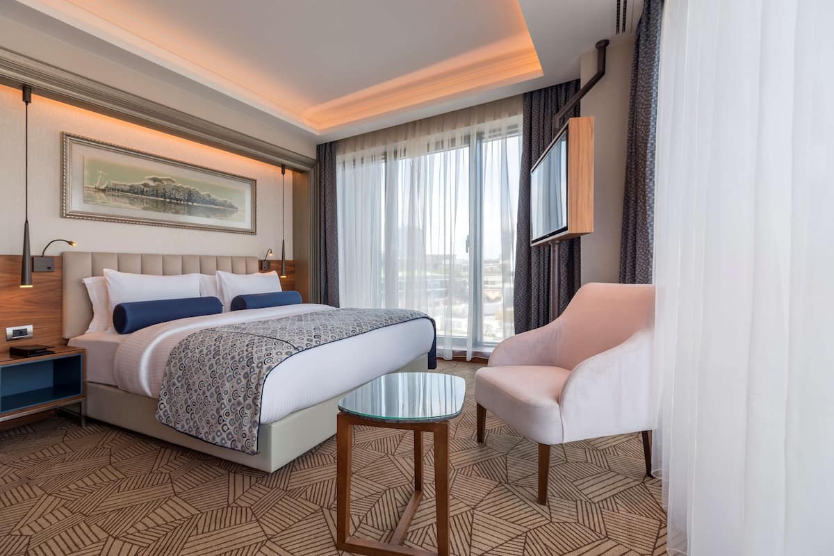Une chambre d’hôtel avec un lit, une table de chevet, une chaise et une petite table.