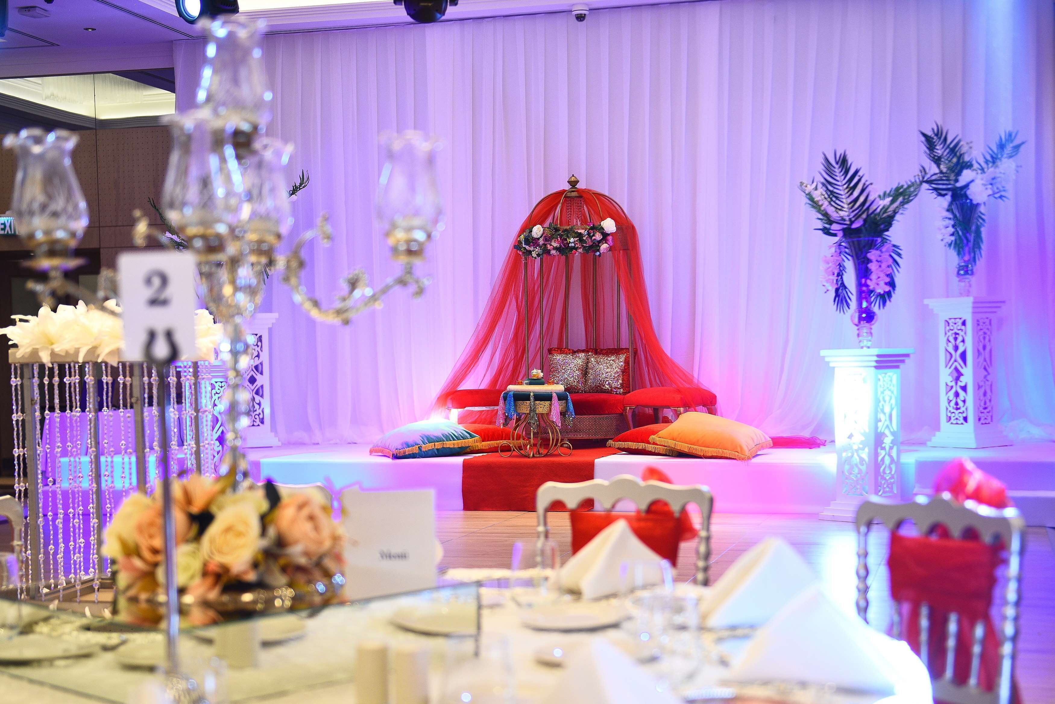 Ein Festsaal mit Bühne, roten Vorhängen und Blumendekorationen.