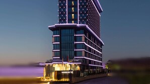 Un hotel moderno con un diseño arquitectónico único, con varios pisos y una entrada destacada con señalización iluminada.