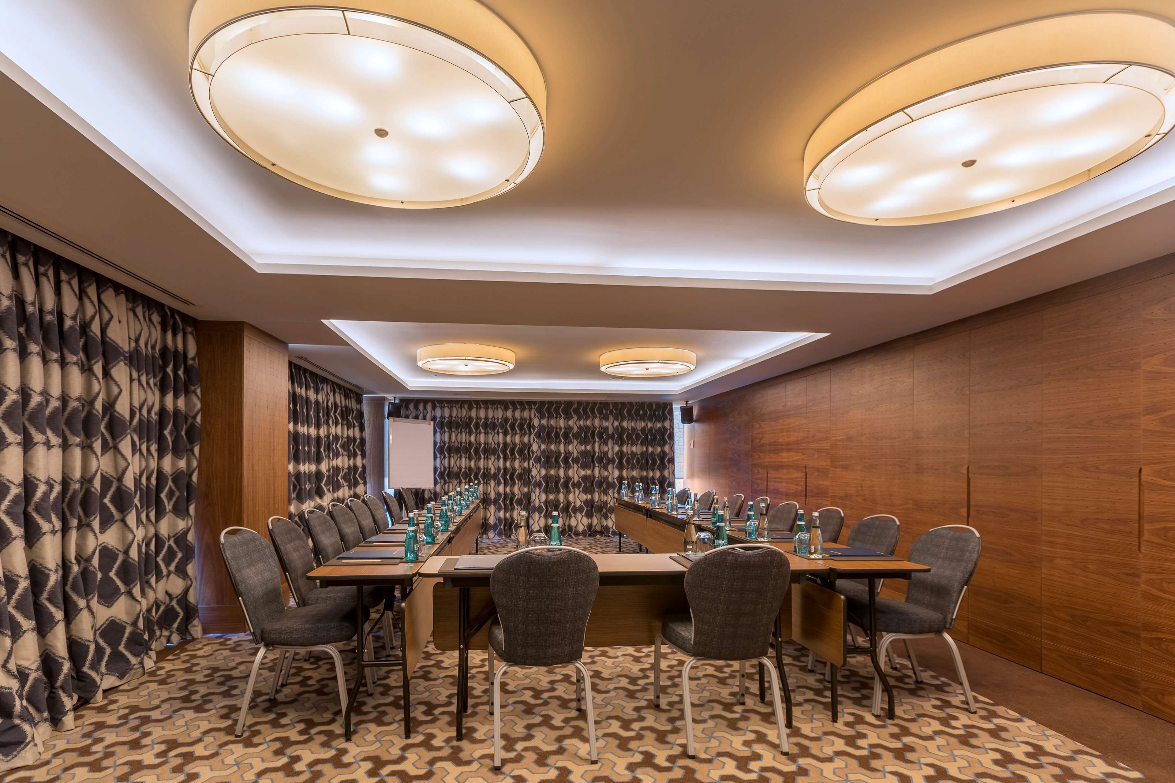 A conference room with a long table, chairs, and a patterned carpet.