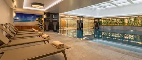 Una piscina techada, sillones reclinables de piscina