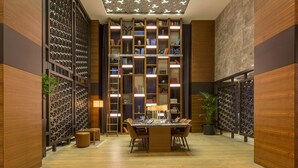 Una biblioteca moderna con una mesa central, estanterías y una iluminación decorativa.