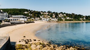 A coastal town with a sandy beach, clear blue water, and buildings on a hillside. - Hôtel Valdys Thalasso & Spa - la Baie (Douarnenez)