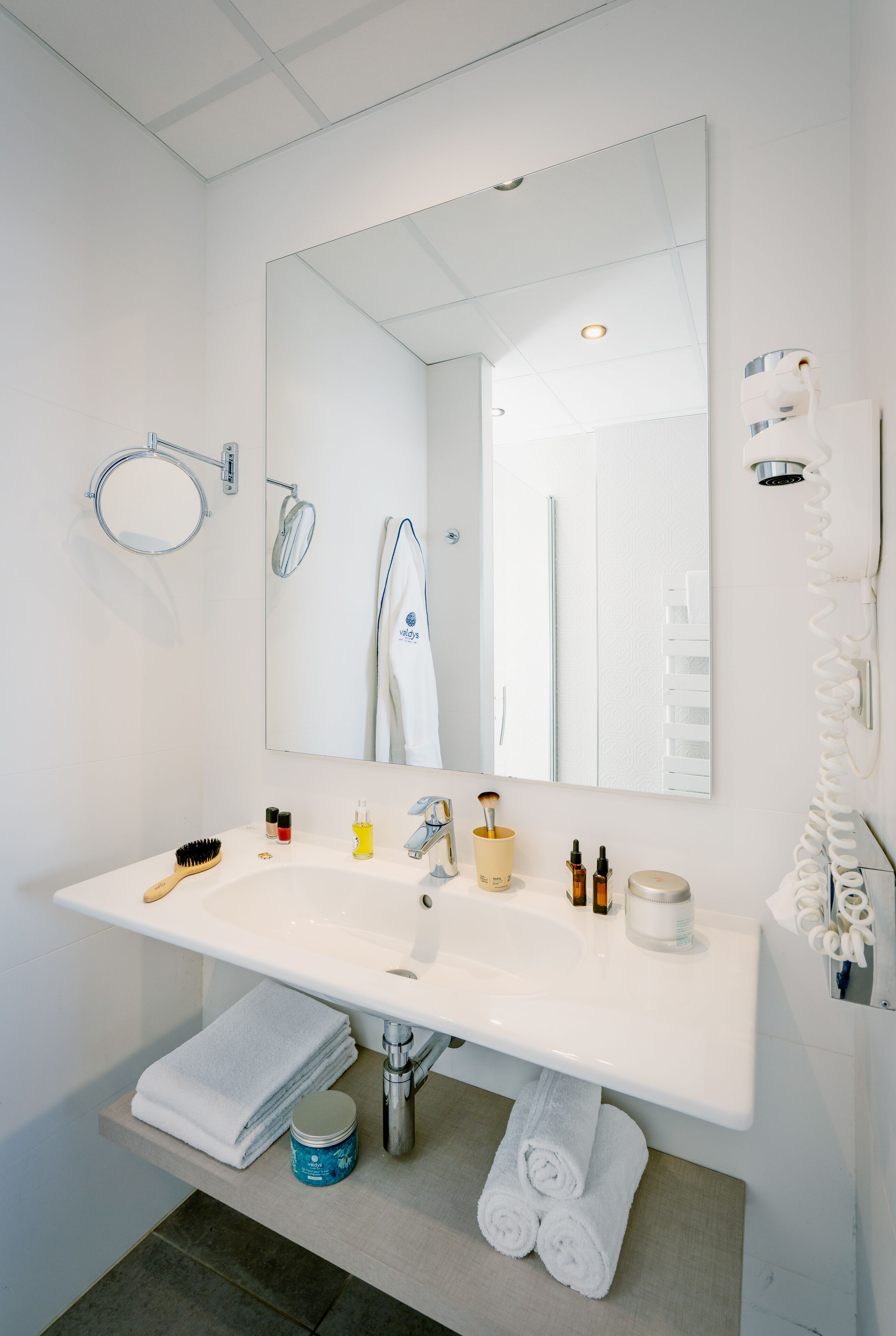 Un baño moderno con lavamanos, espejo y toallero blancos.