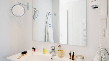 Un baño moderno con lavamanos, espejo y toallero blancos.