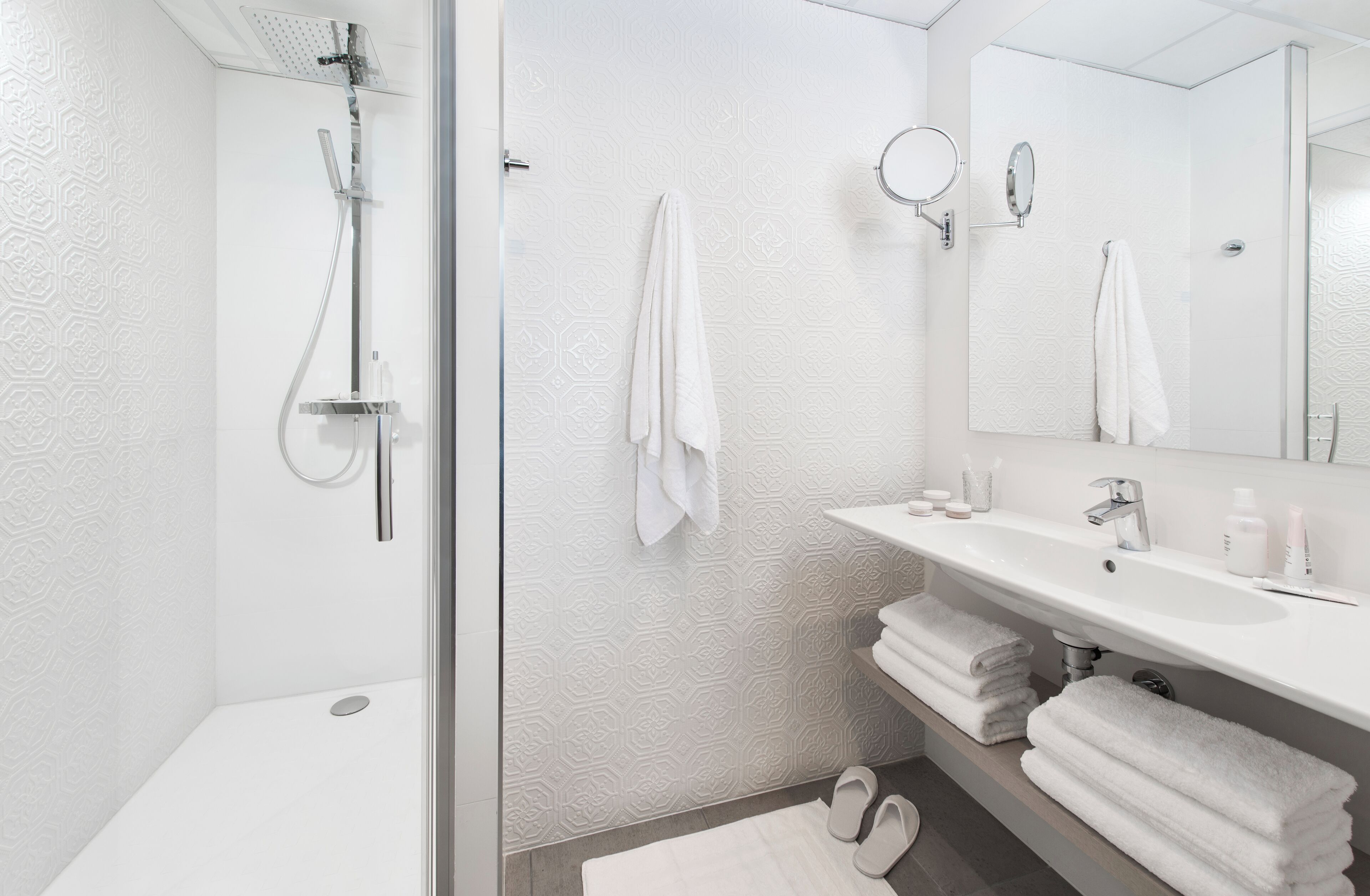 A modern bathroom with a shower, a sink, and a mirror.