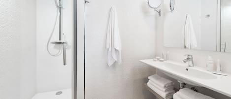 A modern bathroom with a shower, a sink, and a mirror.