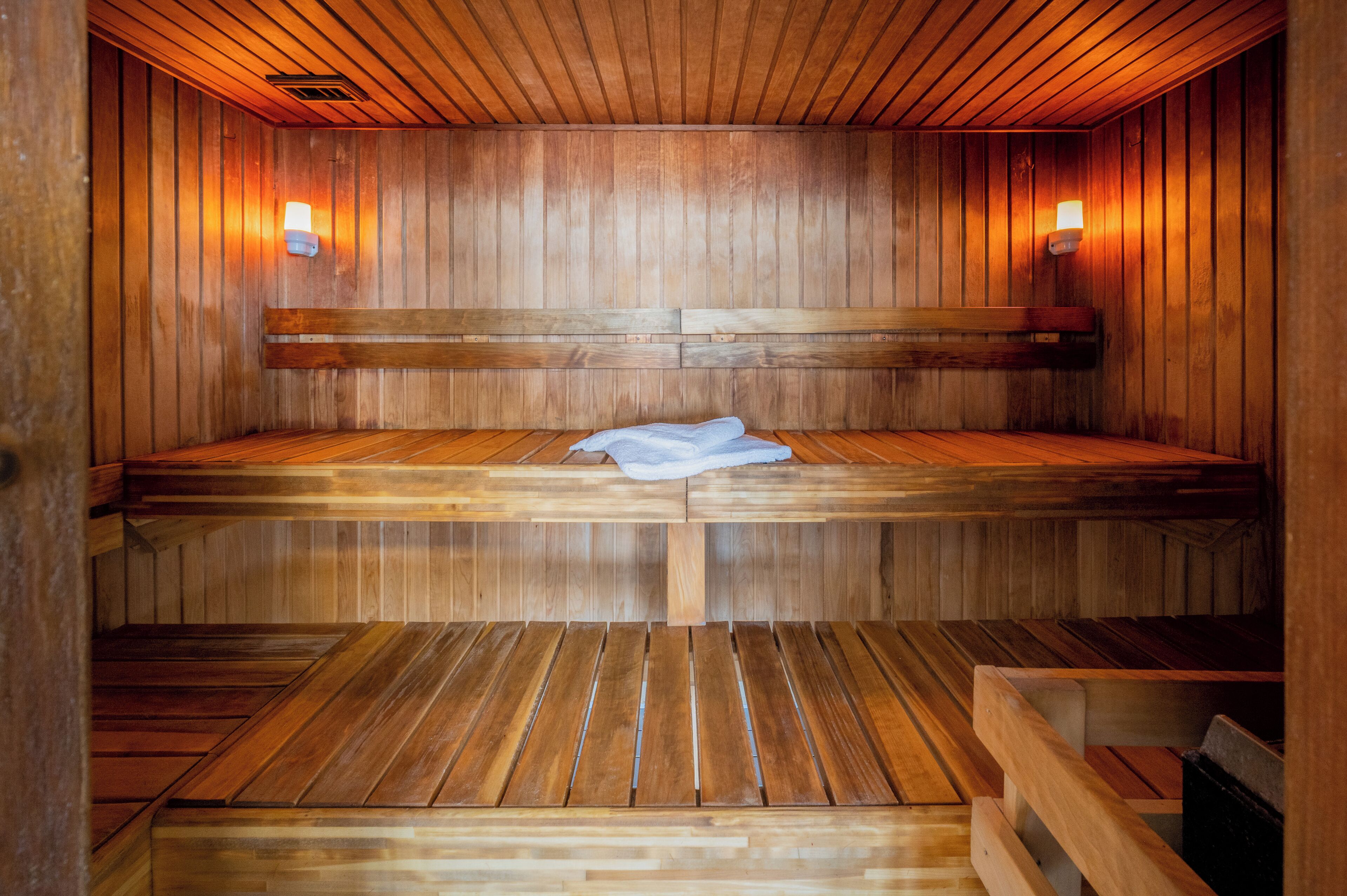 A wooden sauna with benches and wall-mounted lights.