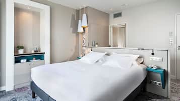 Habitación de hotel moderna con una cama grande, mesitas de noche, un espejo y un estante empotrado con una planta.